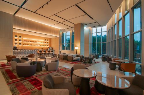 a lobby with tables and chairs and windows at Hyatt Regency Taoyuan International Airport in Dayuan