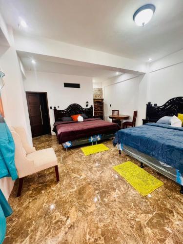 a bedroom with two beds and a chair and a table at Casa Don 20 in San Marcos La Laguna