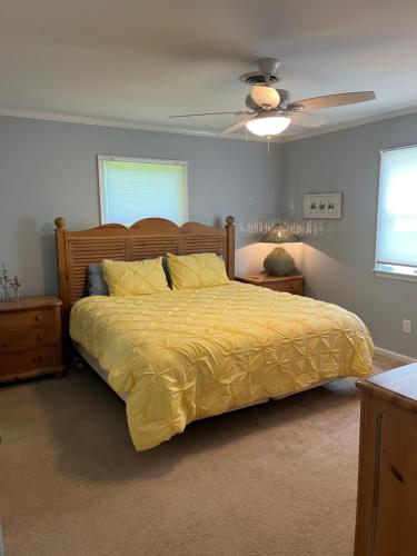 a bedroom with a bed with a yellow comforter and a fan at Flip Flop Drop - Rehoboth Beach - Community Pool! in Rehoboth Beach