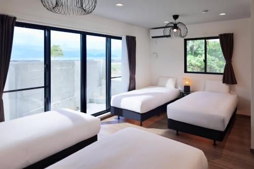 a room with three beds and a large window at クリスタル別荘南城 in Nanjo