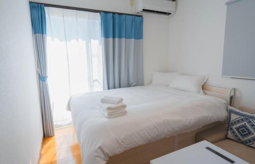 a bedroom with a white bed with towels on it at kugenuma-surf-n-stay in Fujisawa