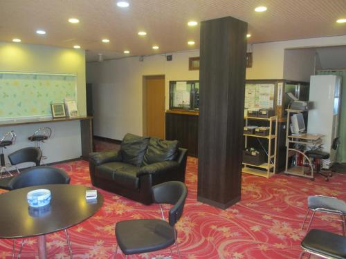 a meeting room with a couch and a table and chairs at Hotel Sankyu in Tsukuba