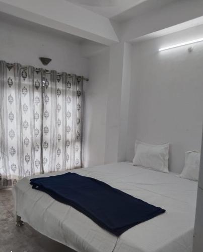 a white bedroom with a bed with a blue blanket on it at Comfi Stay Hotel Bhopal in Bhopal
