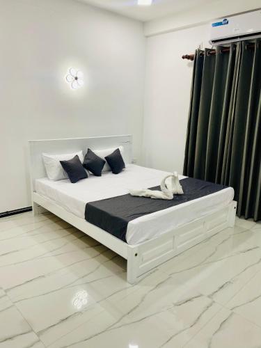 a white bedroom with a white bed with blue pillows at Hotel Jay R in Trincomalee