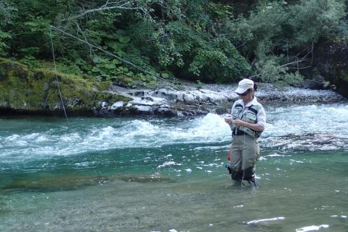 a man standing in a river holding a fishing rod at Guesthouse S in Luče