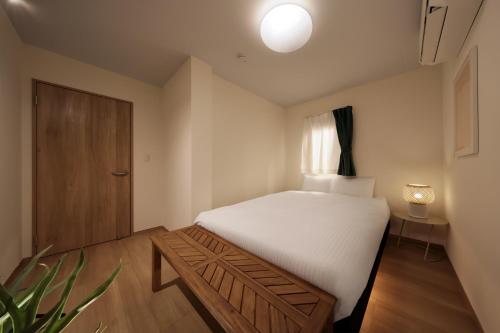 a small bedroom with a white bed and a plant at クリスタル別荘南城 in Nanjo