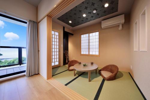 a room with a table and chairs and a large window at クリスタル別荘南城 in Nanjo