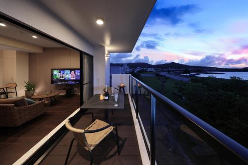 a balcony with a table and a television on a balcony at クリスタル別荘南城 in Nanjo