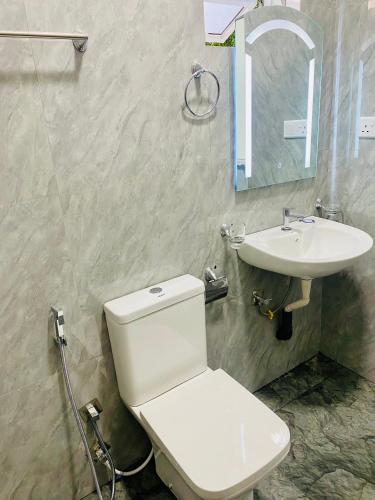 a bathroom with a white toilet and a sink at Hotel Jay R in Trincomalee