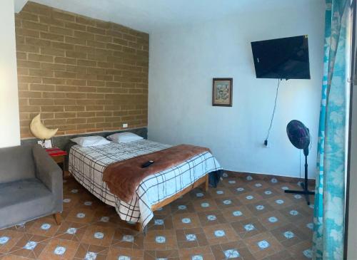 a bedroom with a bed and a brick wall at Casa HUEHUE in Tepoztlán