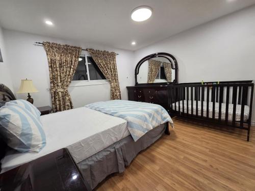 a bedroom with a bed and a crib in it at Three Bedrooms House in Mississauga with free parking Conveniently located with easy access to the airport downtown Toronto major malls and highways for a seamless stay in Mississauga