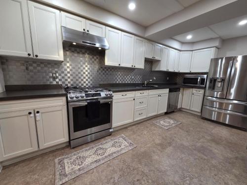 a kitchen with white cabinets and stainless steel appliances at Three Bedrooms House in Mississauga with free parking Conveniently located with easy access to the airport downtown Toronto major malls and highways for a seamless stay in Mississauga