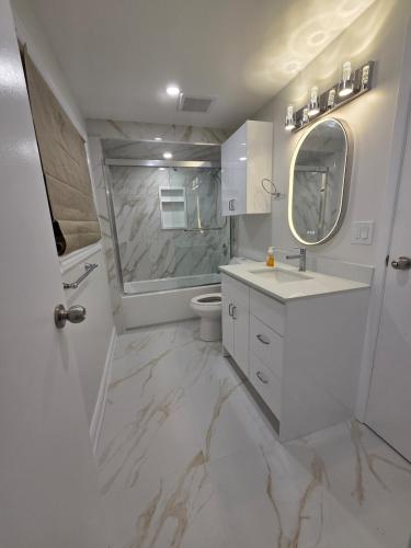 a bathroom with a sink and a toilet and a mirror at Three Bedrooms House in Mississauga with free parking Conveniently located with easy access to the airport downtown Toronto major malls and highways for a seamless stay in Mississauga
