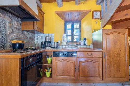 a kitchen with wooden cabinets and a stove at Gîte Le Moulin du Chambon 6/8 pers in Les Bessons
