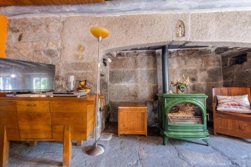 a living room with a green stove and a desk at Gîte Le Moulin du Chambon 6/8 pers in Les Bessons