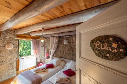 a bedroom with two beds and a stone wall at Gîte Le Moulin du Chambon 6/8 pers in Les Bessons