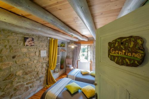 a bedroom with two beds and a stone wall at Gîte Le Moulin du Chambon 6/8 pers in Les Bessons