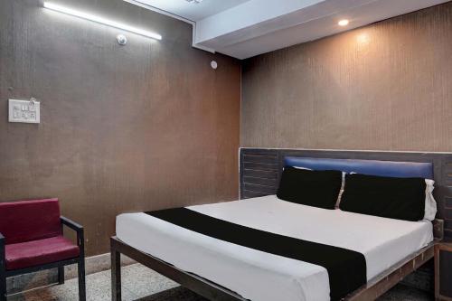Un dormitorio con una cama y una silla roja. en Hotel O Bluebell Inn, en Lucknow