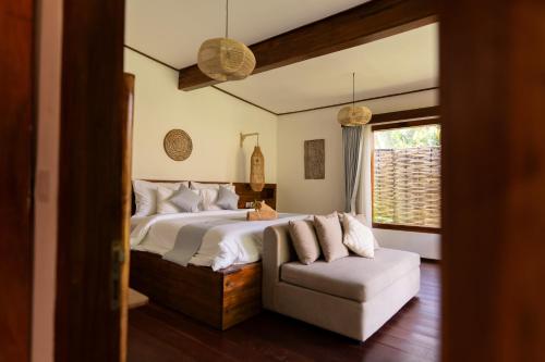 a bedroom with a bed and a couch and a window at AMAN Villas & SPA in Gili Air