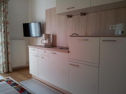a kitchen with white cabinets and a tv on the wall at Haus Amalia in Strobl