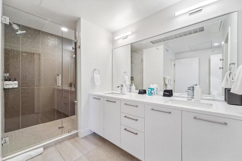 a white bathroom with a shower and two sinks at The Penthouse | Espadin LoHi in Denver