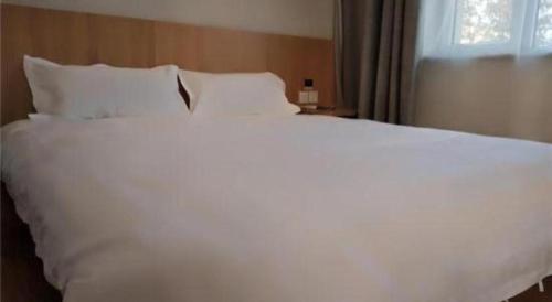 a large white bed with white pillows and a window at PAI Hotels Shijiazhuang Railway Station West Square in Shijiazhuang