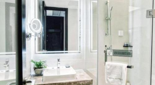 a white bathroom with a sink and a mirror at Xana Hotelle Wuxi Railway Station Zhongshan Road in Wuxi