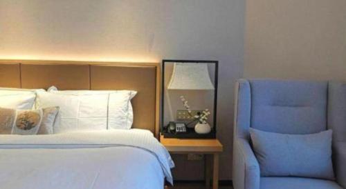 a bedroom with a bed and a blue chair at E-Cheng Hotel Shenyang North Railway Station in Shenyang