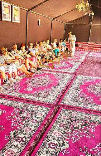 a group of people sitting in a room with pink carpets at The bubble camp in Aqaba