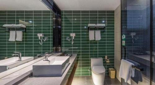 a green tiled bathroom with a sink and a toilet at GreenTree Inn Express Zhangjiagang Hexing Town Shazhou Professional Institue of Technology in Qiwei