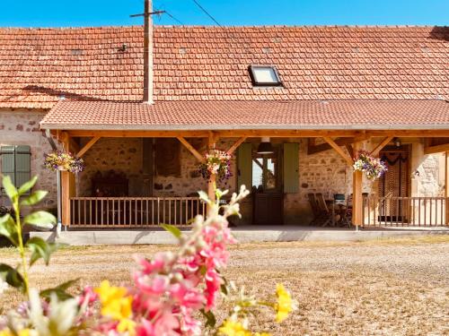 een huis met een rood dak met bloemen ervoor bij chambres d'hôtes Domaine les Grands Pérons in Hérisson