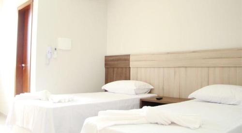 two beds in a room with white sheets and pillows at Hotel PetroShop in Palmas