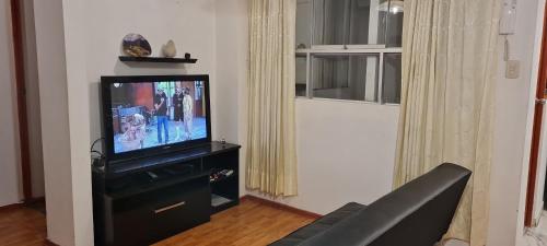 a living room with a flat screen tv on a black cabinet at Kallpa in Cusco