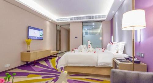 a bedroom with a large white bed and a tv at Lavande Hotel Huizhou Shiwan in Huizhou