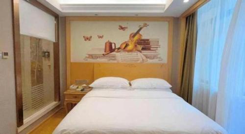 a bedroom with a bed with a guitar on the wall at Vienna Hotel Guangxi Fangcheng in Fangcheng