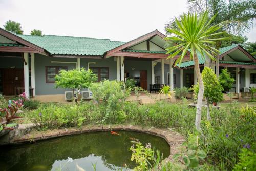 a house with a pond and a palm tree at Rage Fight Academy in Pattaya South