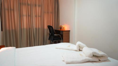 a bedroom with a white bed and a black chair at Hôtel Moukawama Restaurant & SPA Dakhla in Dakhla