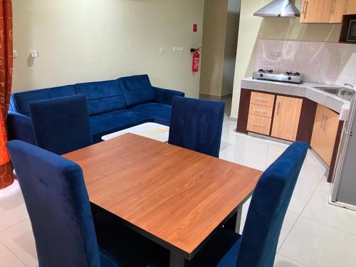 a living room with a wooden table and blue chairs at Résidence Romacy, appartement 2 chambres avec balcon à Ahala, quartier résidentiel de Yaoundé in Yaoundé