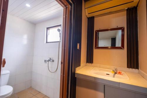 a bathroom with a sink and a toilet and a mirror at Teba House Ubud by ecommerceloka - CHSE Certified in Ubud