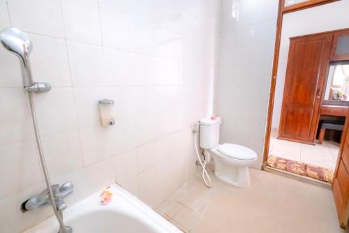 a bathroom with a toilet and a bath tub at Teba House Ubud by ecommerceloka - CHSE Certified in Ubud