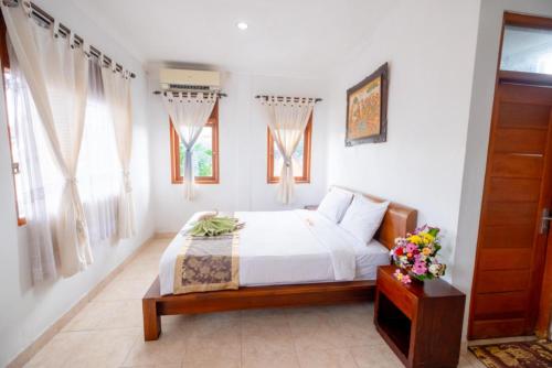 a bedroom with a bed with white sheets and windows at Teba House Ubud by ecommerceloka - CHSE Certified in Ubud