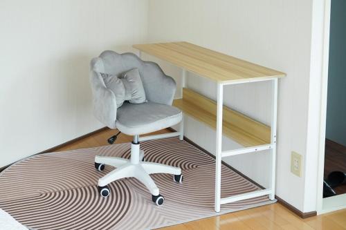 a chair sitting on a rug next to a desk at Aonoyado 碧の宿べっぷ駅前町 in Beppu