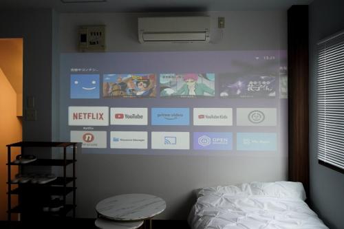 a bedroom with a large screen on the wall at Aonoyado 碧の宿べっぷ駅前町 in Beppu