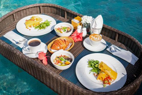 乌布戈雅精品度假村的餐桌,餐桌上放着食物盘,靠近水面