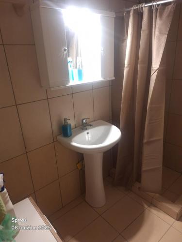 a bathroom with a white sink and a window at Akrotirio Tainaro House in Marmari