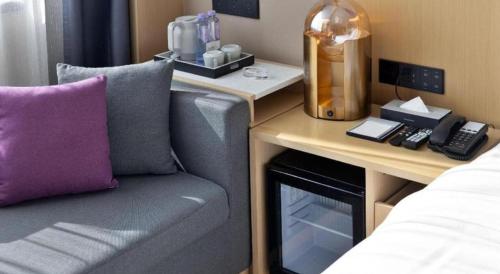 a room with a couch and a desk with a phone at Lavande Hotel Guangzhou Quzhuang Metro Station in Guangzhou