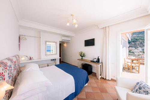 a bedroom with a bed and a chair and a window at Villa Anfitrite in Positano