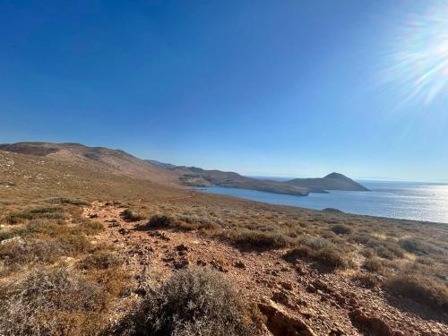 a view of the ocean from a hill with the sun at Akrotirio Tainaro House in Marmari