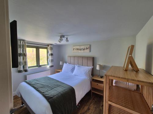 a bedroom with a bed and a wooden desk at Birch Banc Retreats - Bedw in Llanidloes