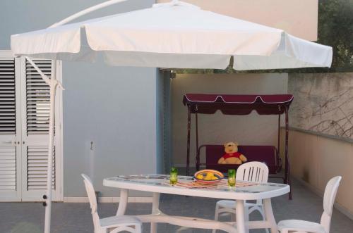 a table with a teddy bear sitting in a chair under an umbrella at Cocorito Apartments in Punta Secca